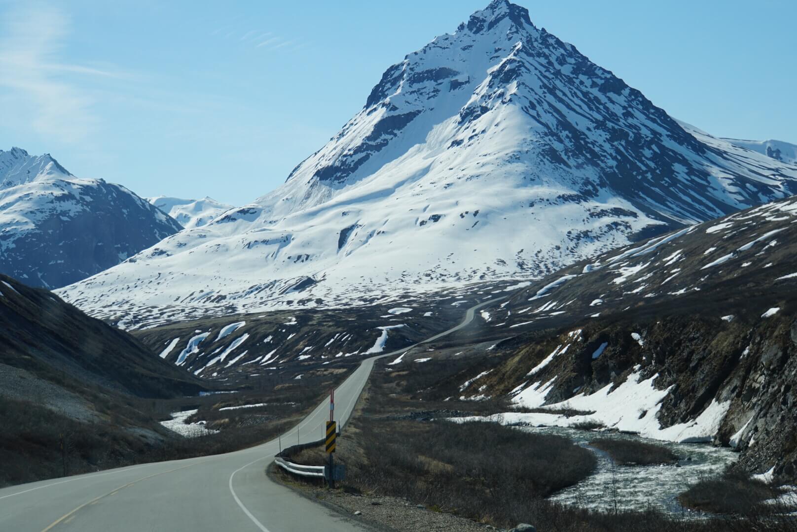 Snowy mountain with winding road beneath.